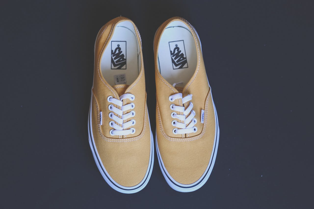 Pair of stylish yellow sneakers on a black background showcasing fashion and footwear design.